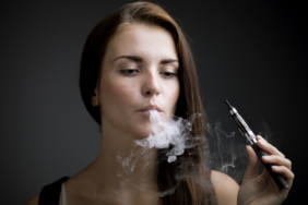 Elegant woman smoking e-cigarette with smoke