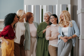 Group of happy mature women bonding and smiling while standing in the office together
